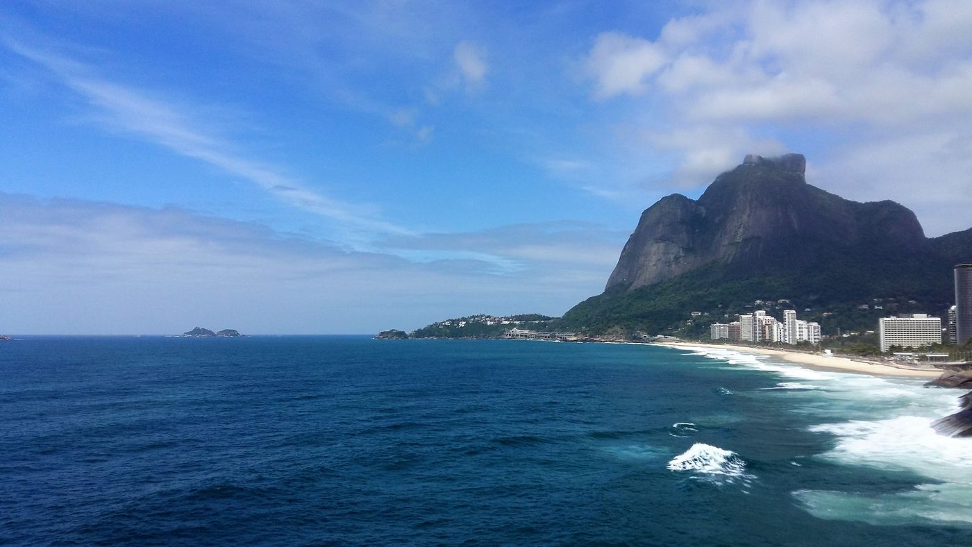 Waves breaking below the coast road, with São Conrado Beach and Pedra da Gávea across the water