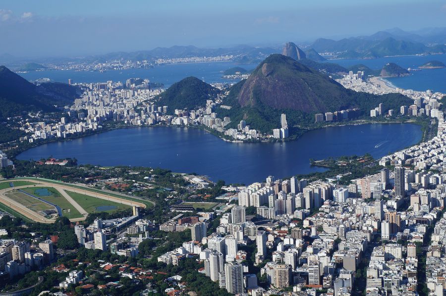 Lagoa Rodrigo de Freitas seen from above, ringed by apartment blocks, with the Jockey Club racecourse in front and Sugarloaf Mountain on the skyline