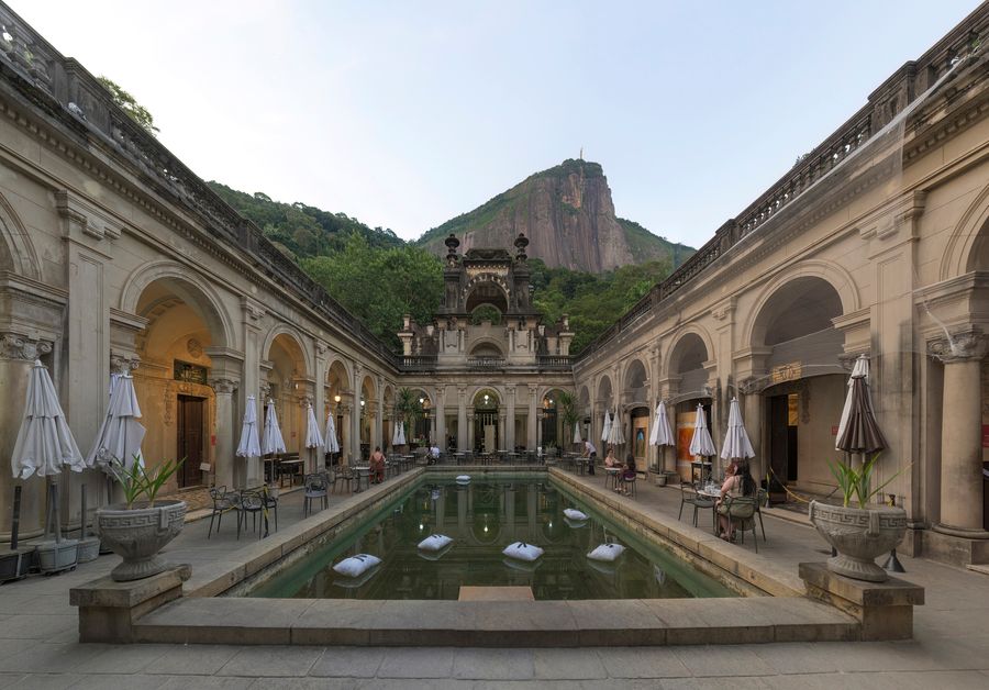 The arcaded courtyard of the Parque Lage mansion around a long pool, with café tables and Corcovado and Christ the Redeemer above
