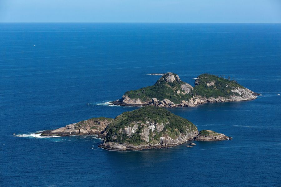 Aerial view of the rocky, forested Ilhas Tijucas surrounded by deep blue sea