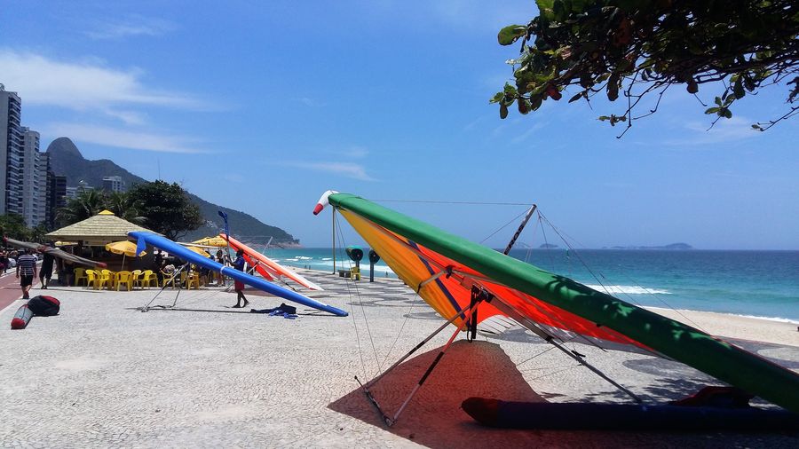Colourful hang-gliders resting on the promenade at São Conrado Beach, beside the sand and the sea